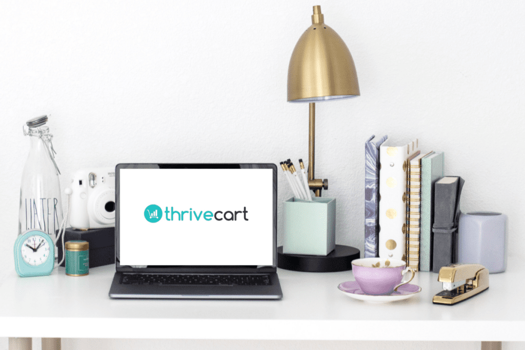 Home office desk with books and a laptop displaying the logo for a business automation tool called Thrivecart.